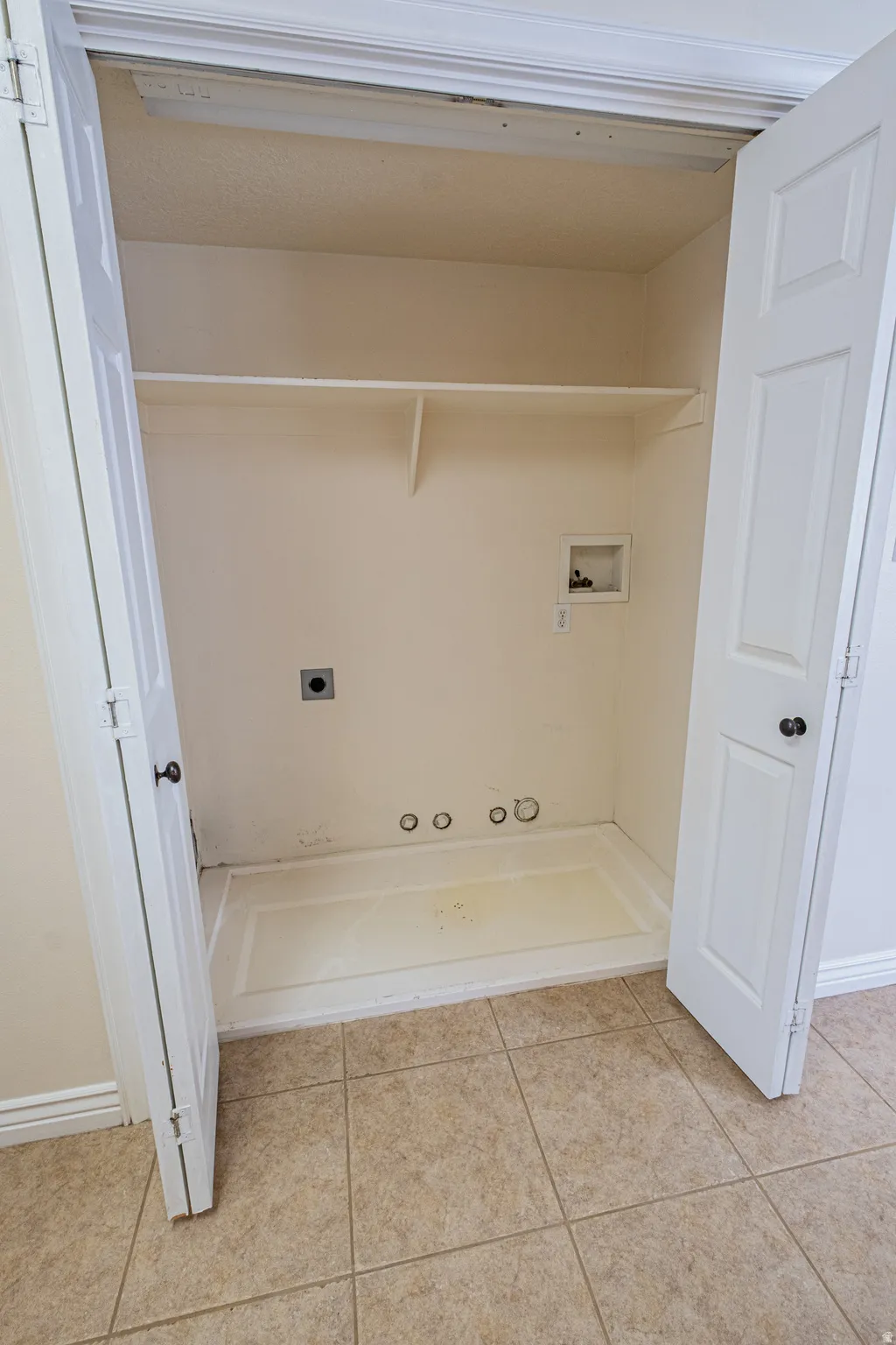 Laundry area with hookup for an electric dryer, hookup for a washing machine, light tile patterned floors, and gas dryer hookup