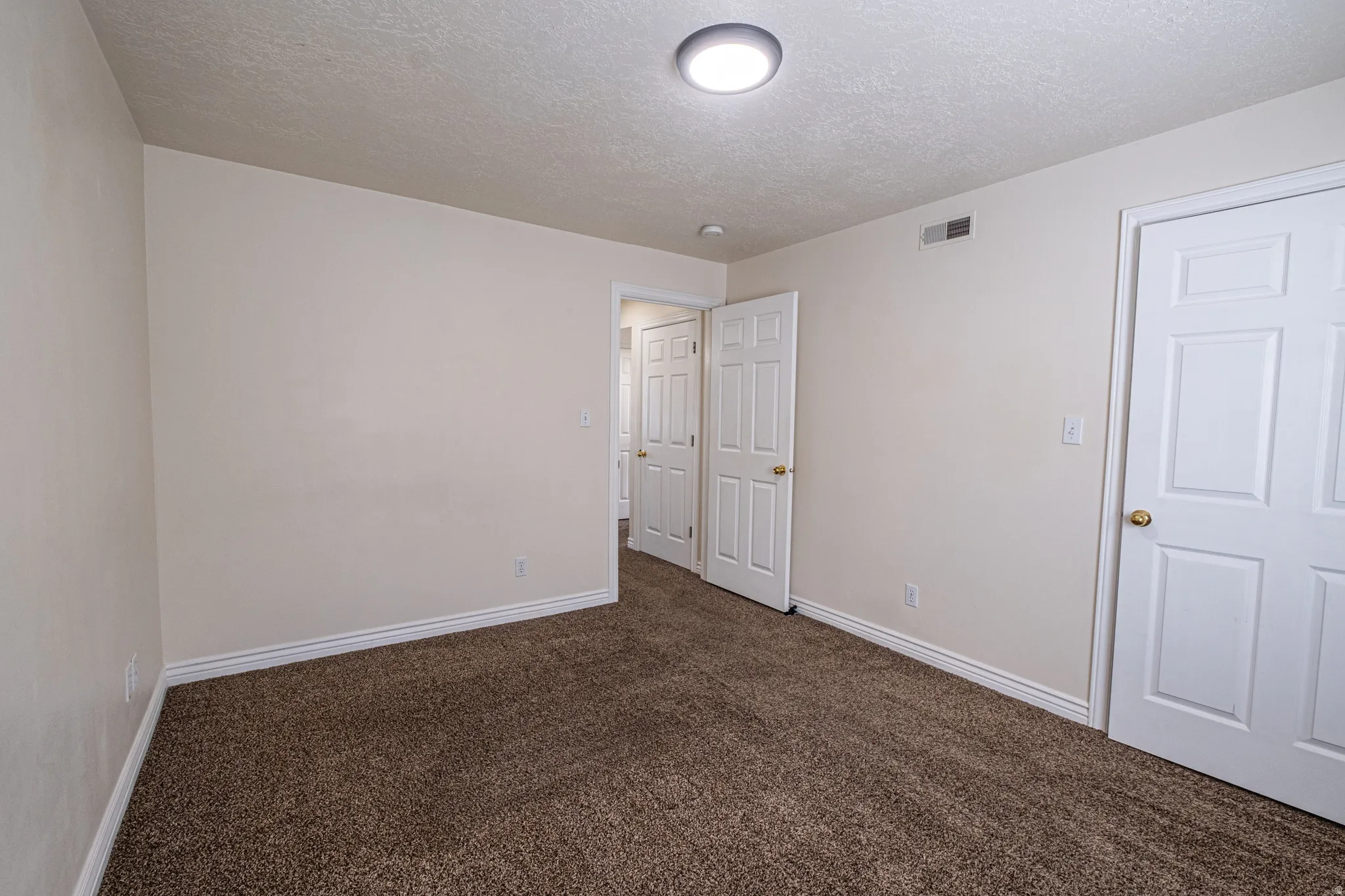 Unfurnished bedroom featuring dark colored carpet and a textured ceiling