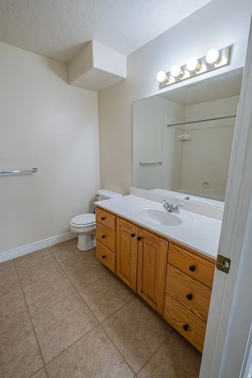 Bathroom featuring vanity, a textured ceiling, light tile patterned floors, and a shower