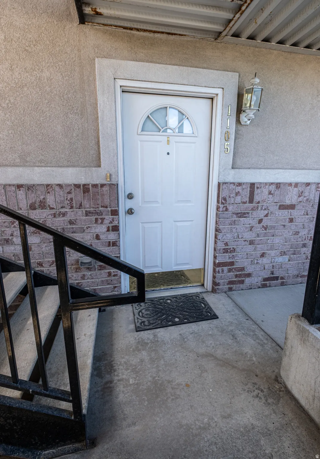 Doorway to property featuring brick siding and stucco siding