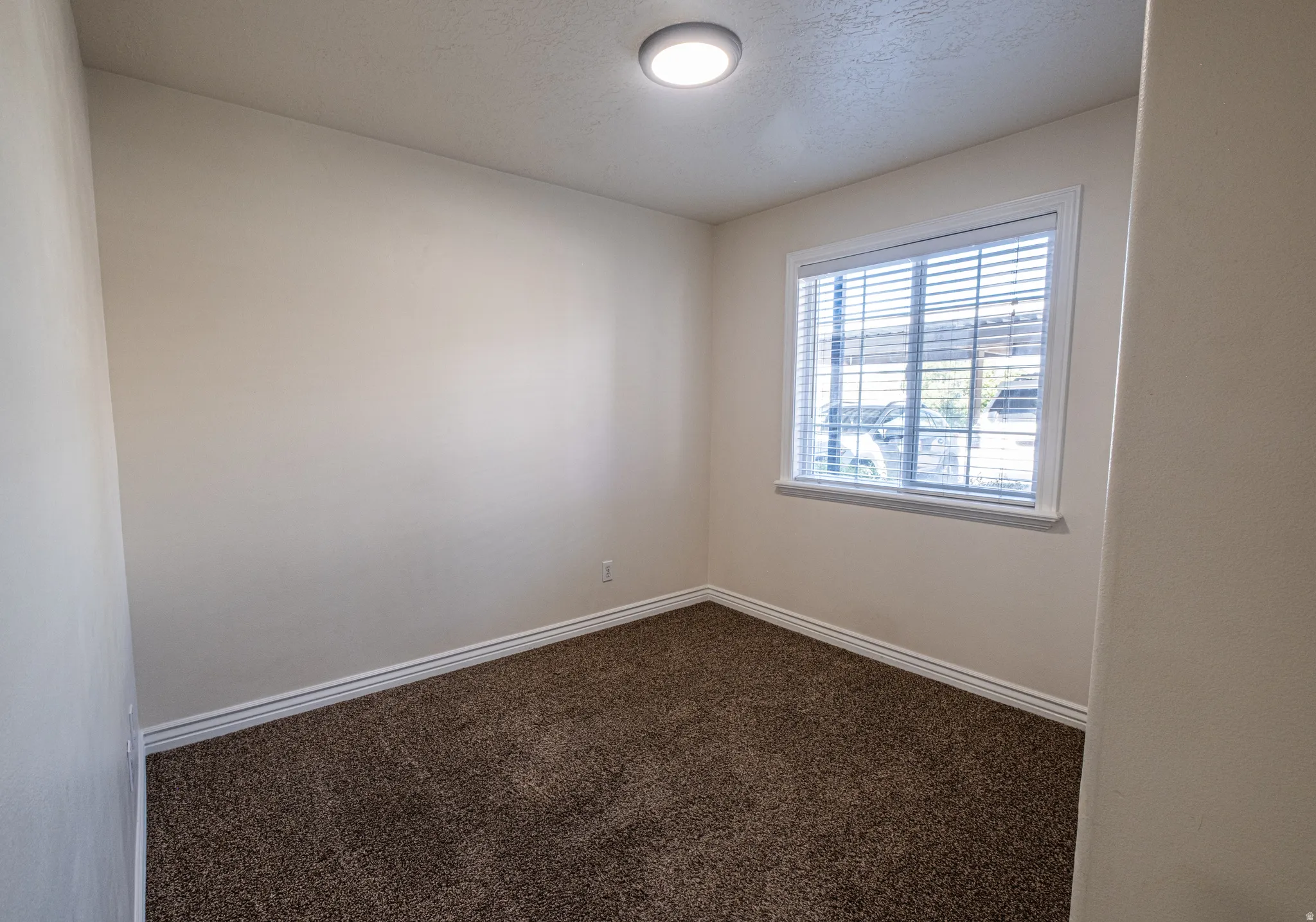 Spare room with dark carpet and a textured ceiling