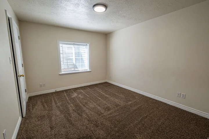 Unfurnished room featuring dark colored carpet and a textured ceiling
