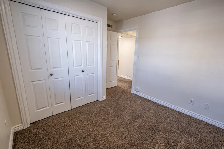 Unfurnished bedroom with dark carpet and a closet