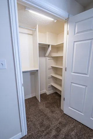 Walk in closet featuring dark carpet
