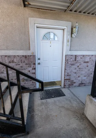Doorway to property featuring brick siding and stucco siding