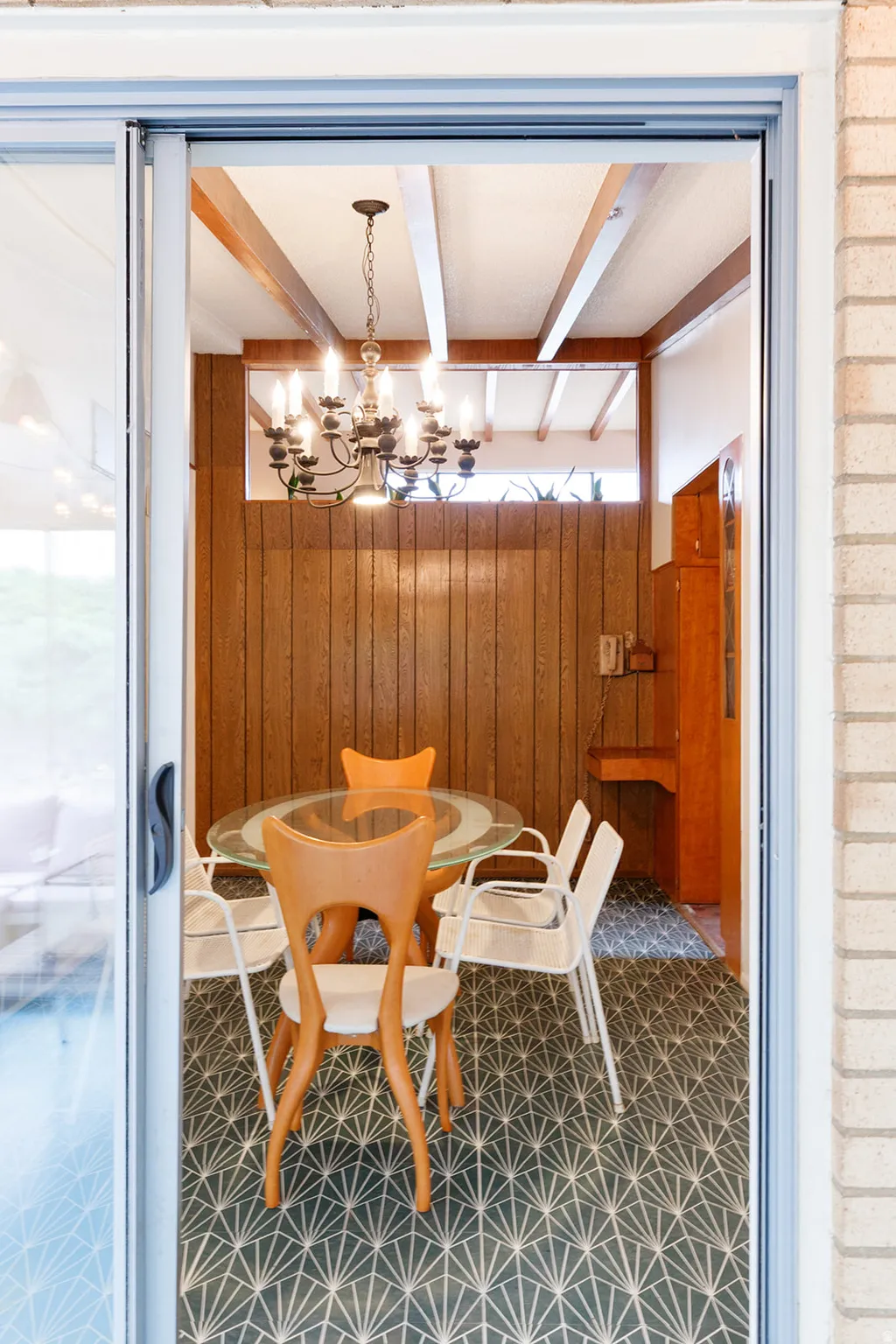 Dining space with wood walls, a chandelier, tile patterned floors, and beam ceiling