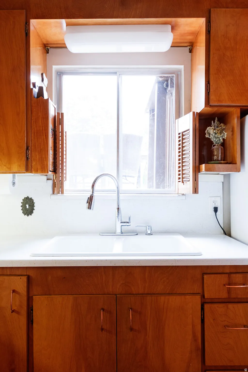 Kitchen with wood finish cabinetry, light countertops, and open shelves