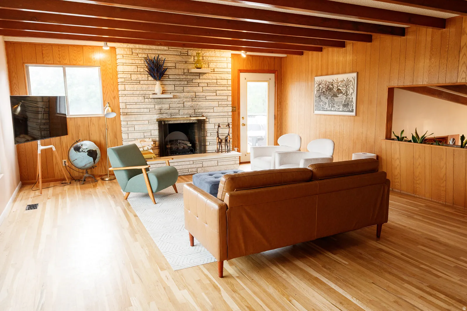 Living room featuring wooden walls, beam ceiling, wood finished floors, and a fireplace