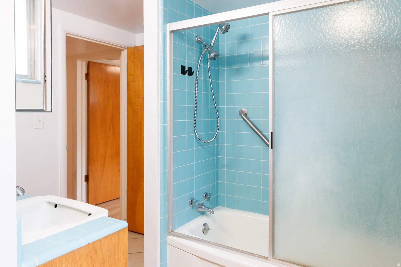 Full bath featuring bath / shower combo with glass door and a sink