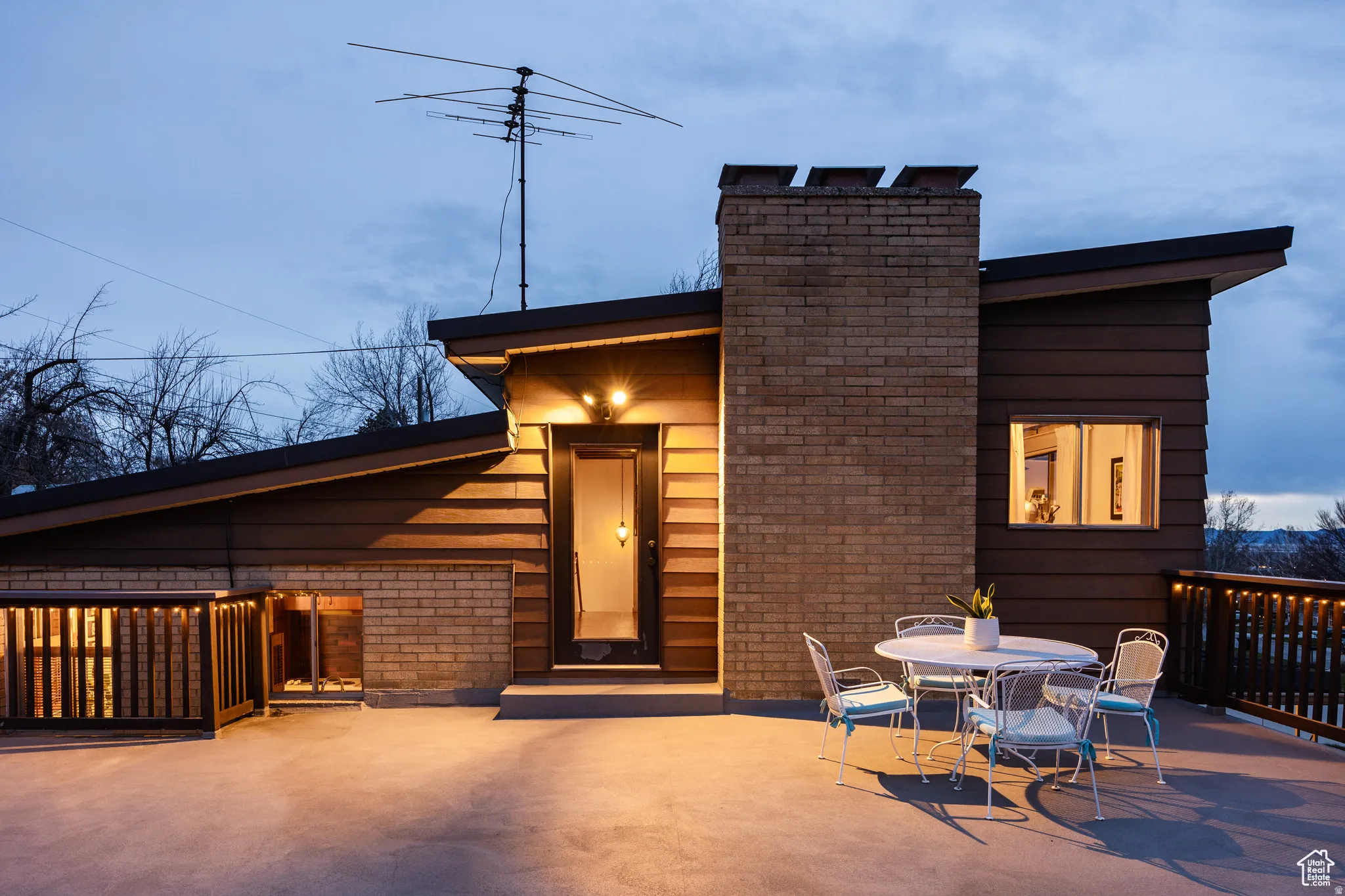 View of front of property featuring brick siding, a chimney, outdoor dining area, and a patio