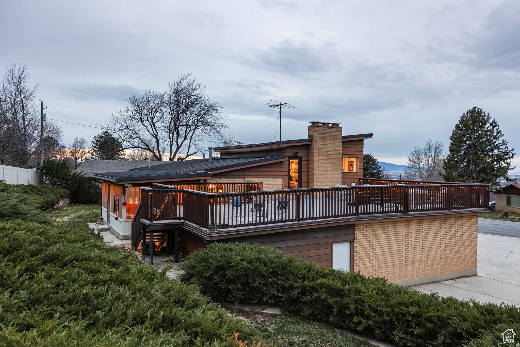 Back of house featuring a wooden deck, brick siding, and a chimney