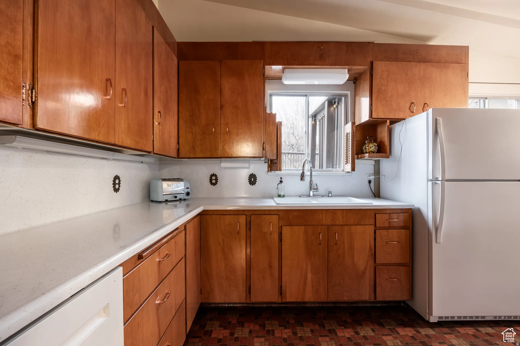 Kitchen with white appliances, wood finish cabinetry, and light countertops