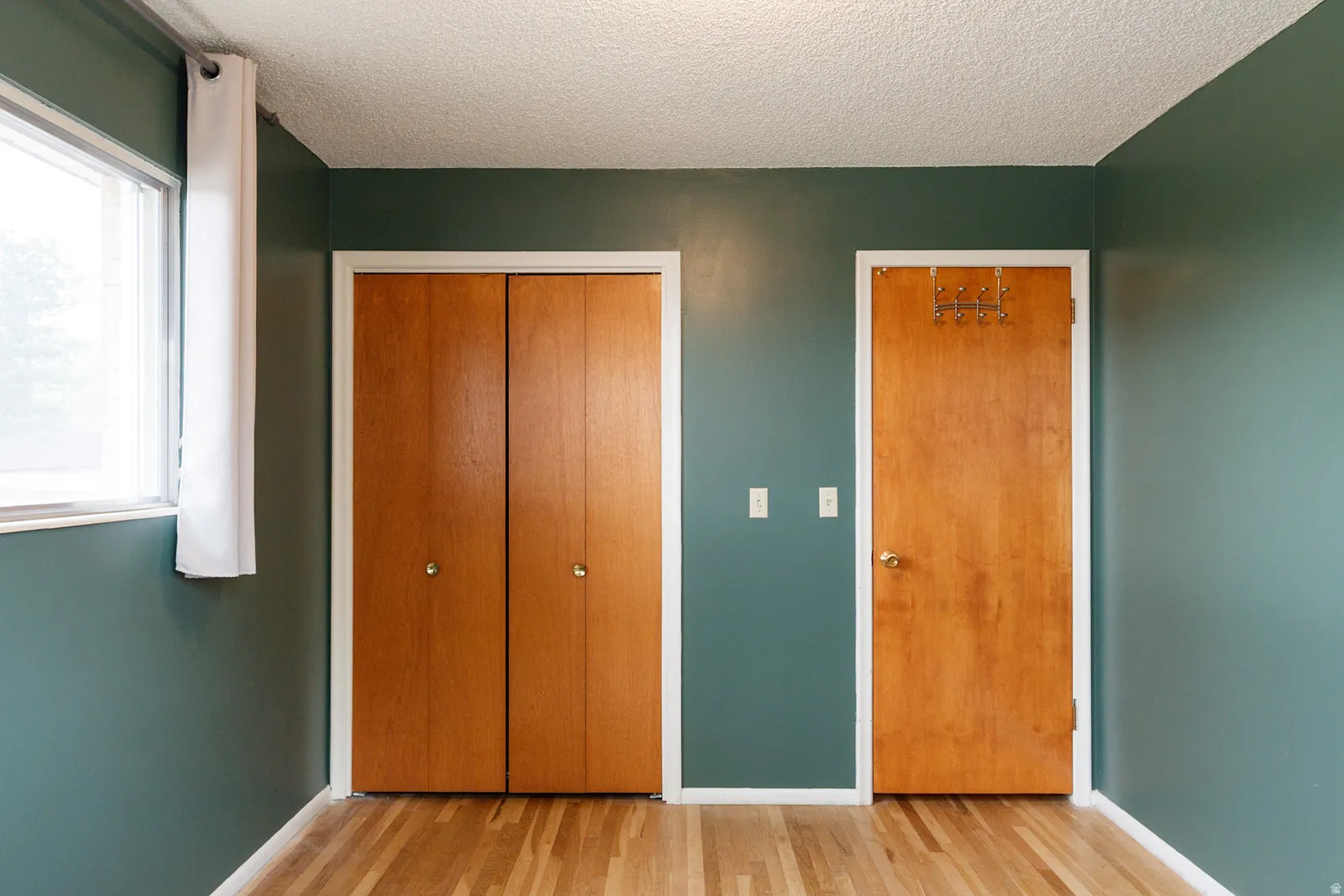 Unfurnished bedroom featuring light wood finished floors, a textured ceiling, and a closet