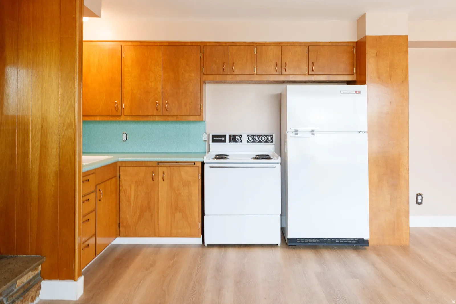 Kitchen with white appliances, light countertops, light wood-style floors, and wood finish cabinets