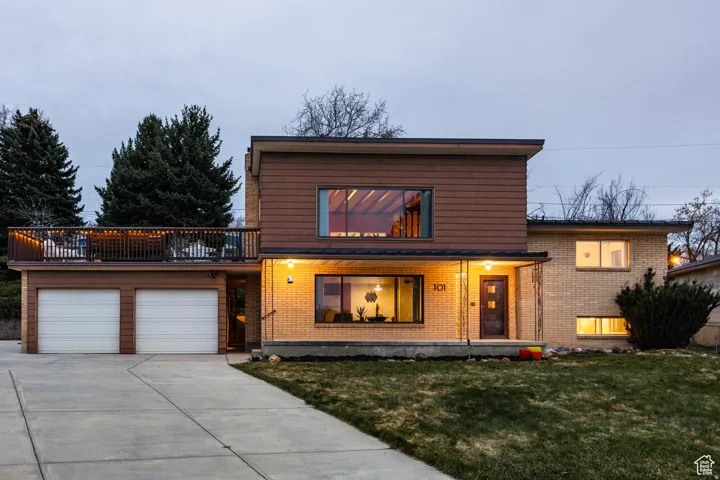 View of front of house with brick siding, a garage, driveway, and a front lawn