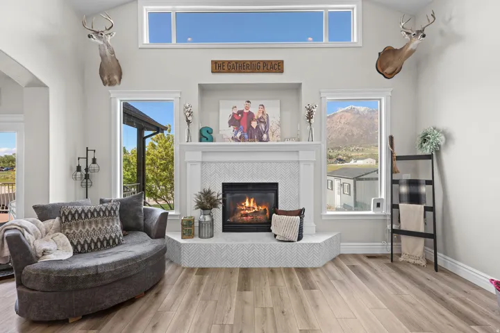 Sitting room with a high ceiling, light wood-type flooring, and a tiled fireplace