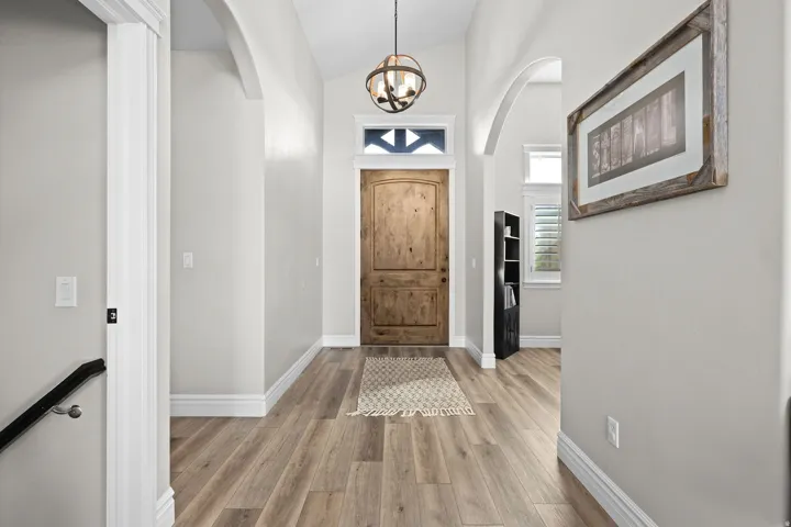 Entrance foyer with lofted ceiling, suspended lighting, light wood-type flooring, and arched walkways