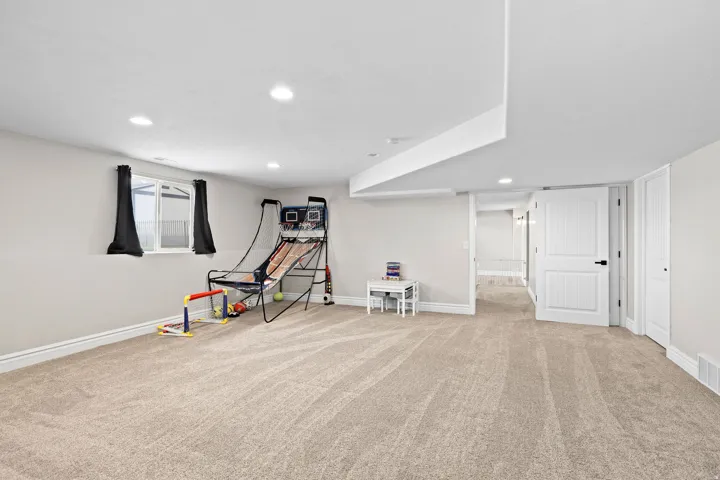 Recreation room with light carpet and recessed lighting