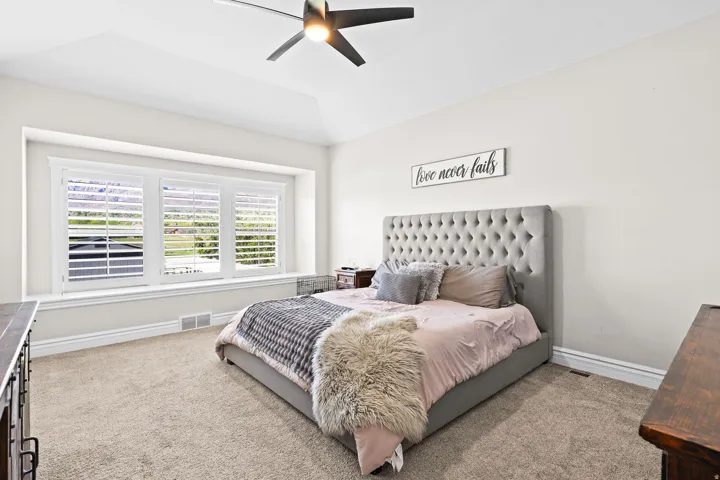 Carpeted bedroom with a tray ceiling and a ceiling fan