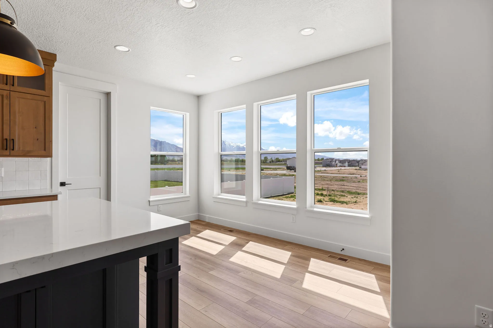 Unfurnished dining area with light wood-type flooring, a textured ceiling, recessed lighting, and a mountain view