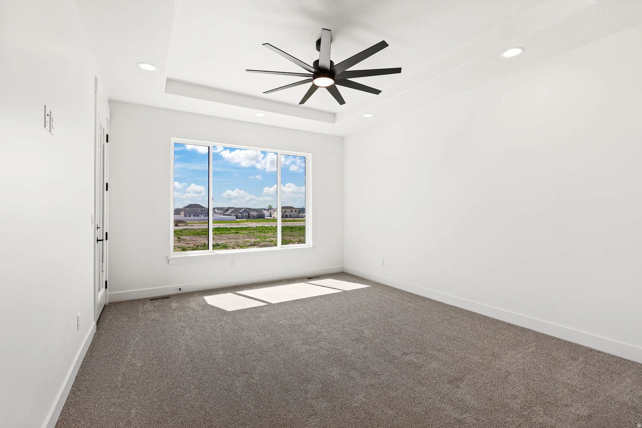 Unfurnished room with dark carpet, a ceiling fan, a raised ceiling, and recessed lighting