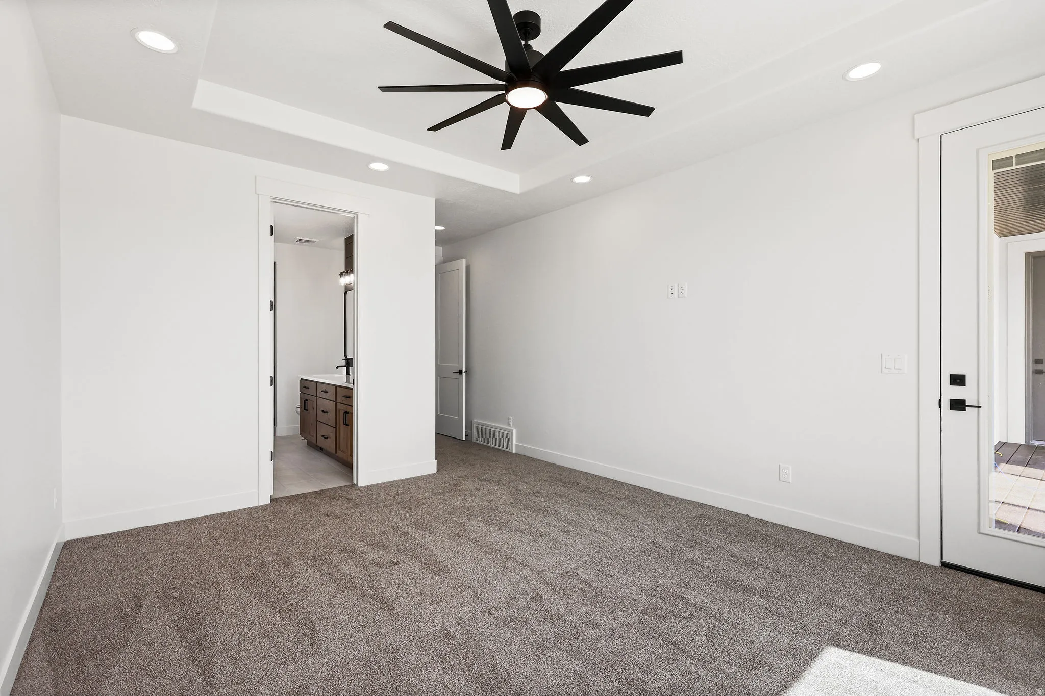 Unfurnished bedroom featuring light colored carpet, connected bathroom, recessed lighting, and ceiling fan
