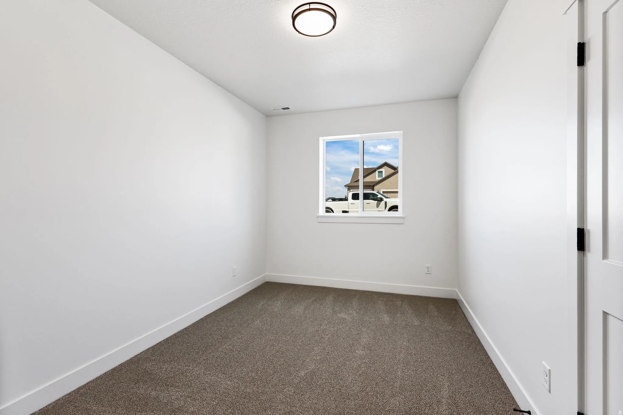 Empty room featuring baseboards and dark carpet