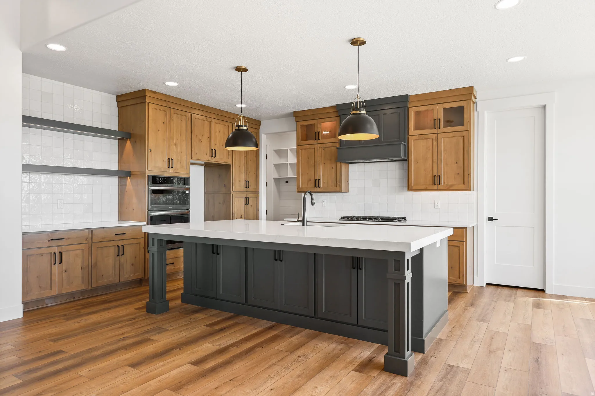 Kitchen with open shelves, dual tone cabinetry, a large island, light wood finished floors, and stainless steel double oven