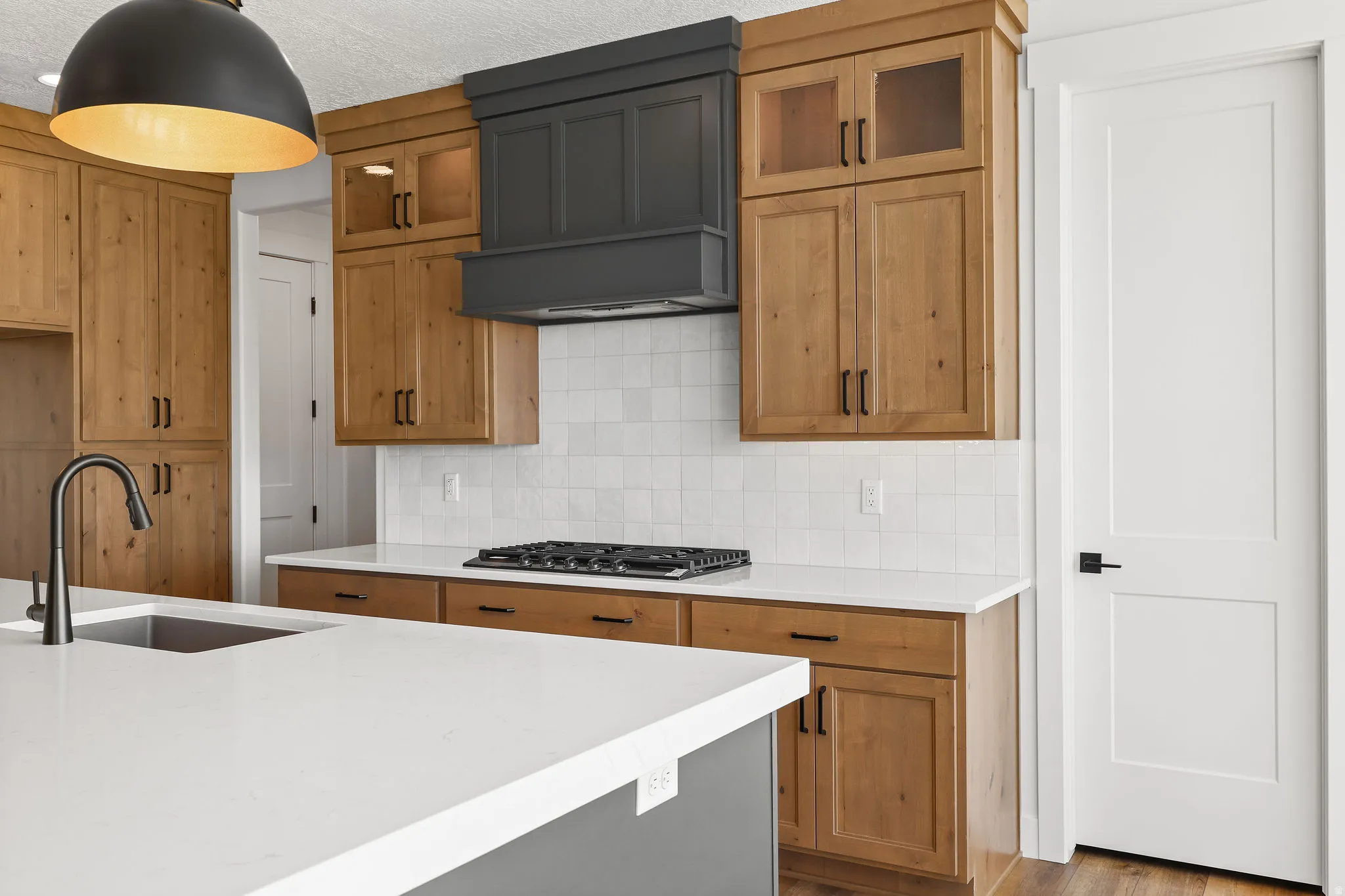 Kitchen with decorative backsplash, light stone counters, dark wood-style floors, wood finish cabinetry, and glass fronted cabinets