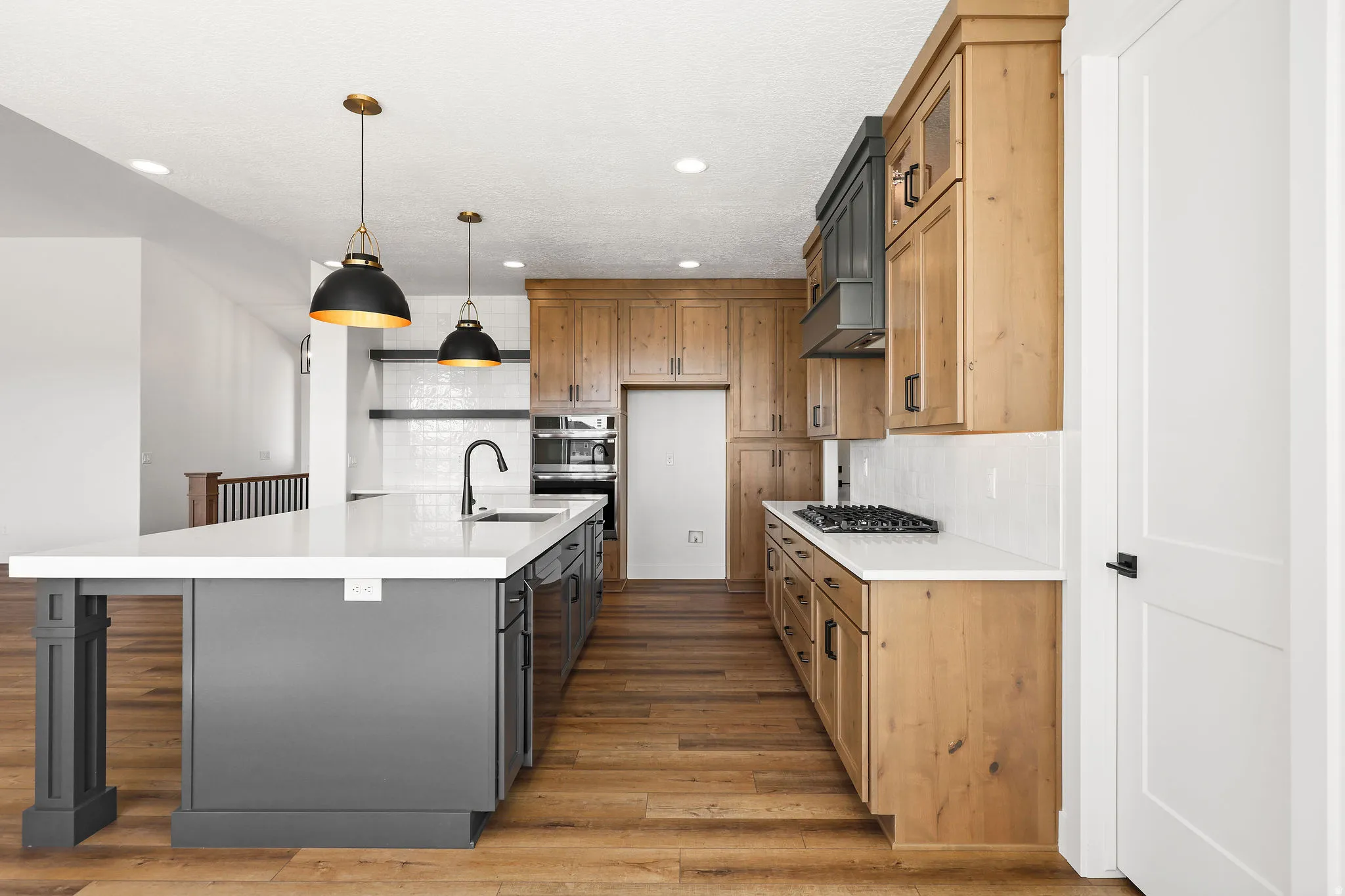 Two tone kitchen with dual tone cabinets, decorative backsplash, a large island, a breakfast bar, and light wood-style flooring