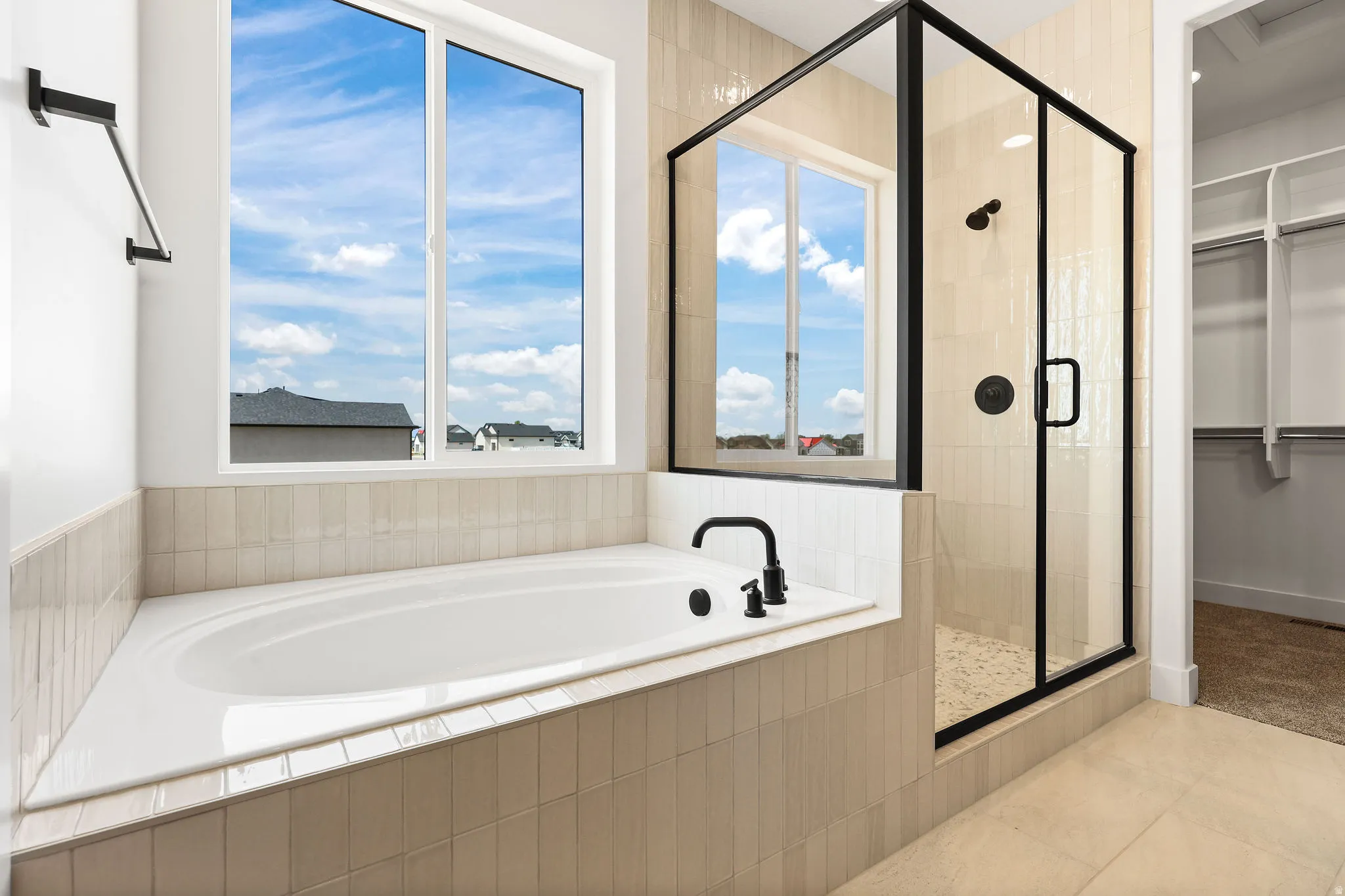 Bathroom featuring a walk in closet, a garden tub, a stall shower, light tile patterned floors, and plenty of natural light