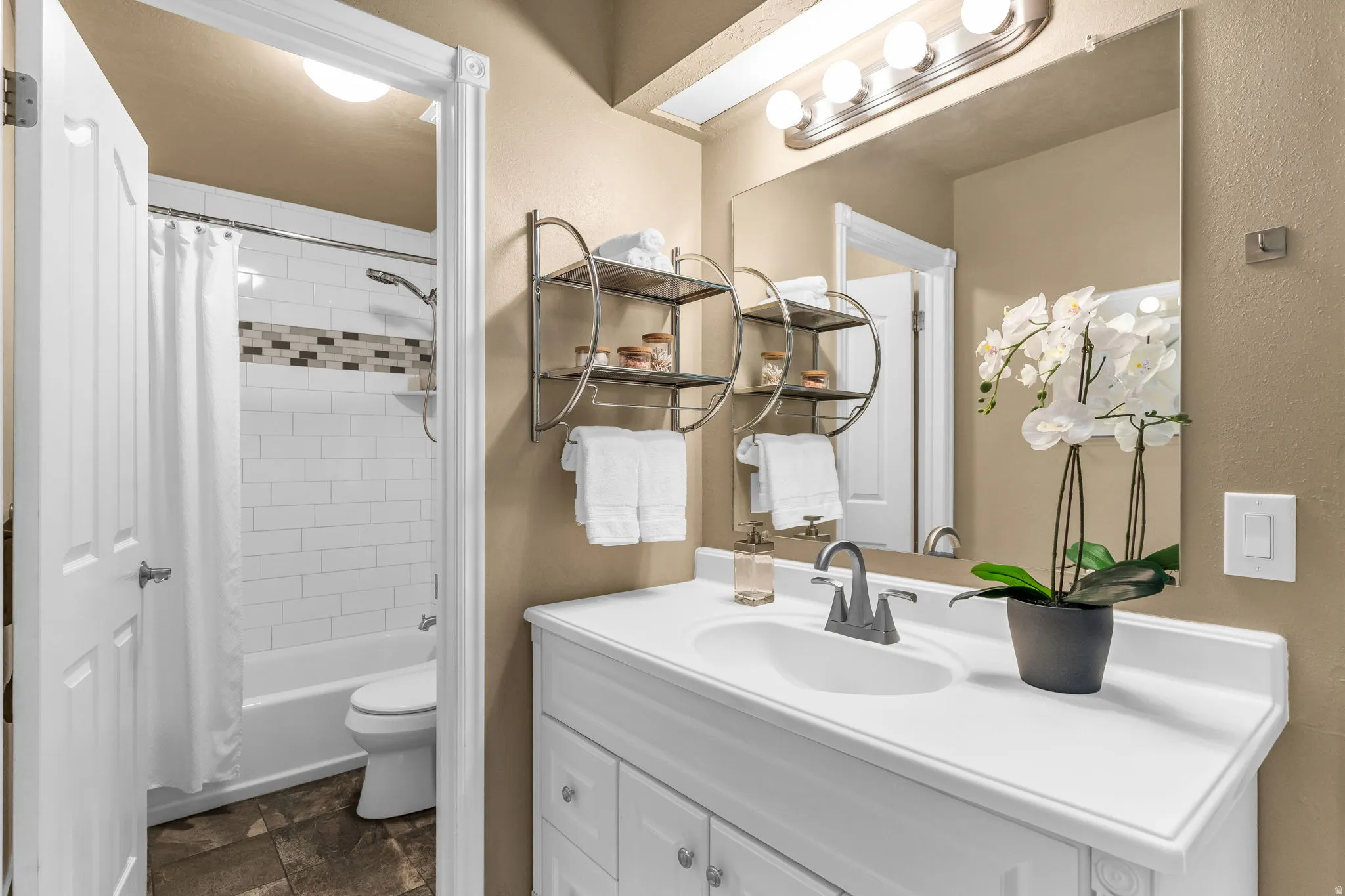 Full bathroom featuring vanity, shower / bath combination with curtain, and stone finish flooring