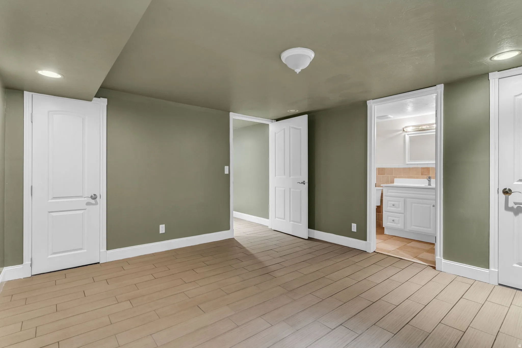 Unfurnished bedroom featuring recessed lighting, wood finish floors, and connected bathroom