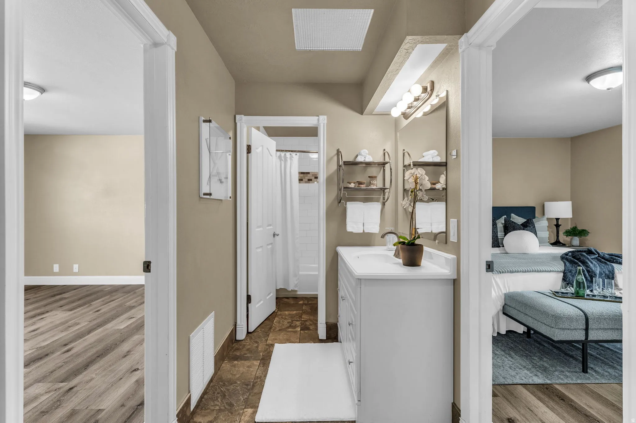 Ensuite bathroom with vanity, curtained shower, and dark stone finish flooring