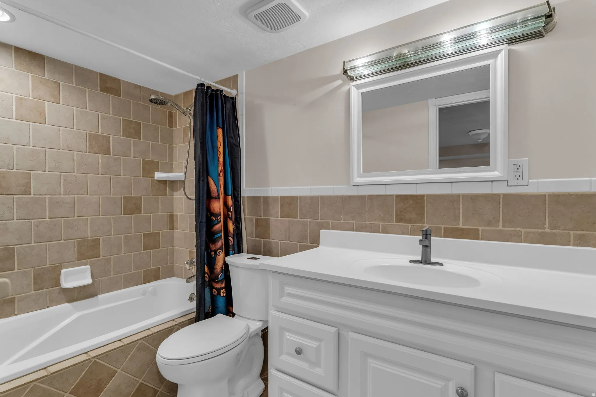 Full bathroom with vanity, shower / bath combo, and tile walls