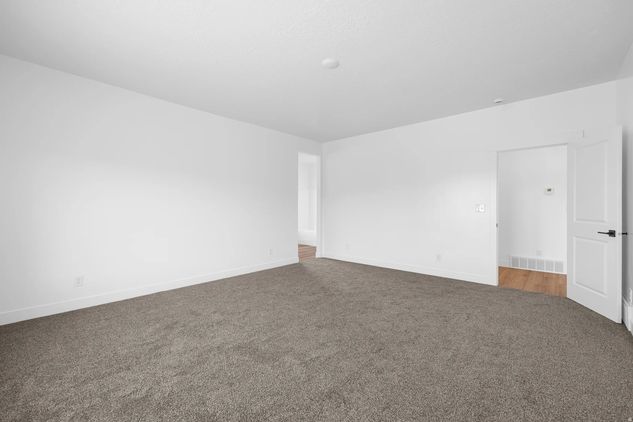 Spare room featuring carpet flooring and baseboards