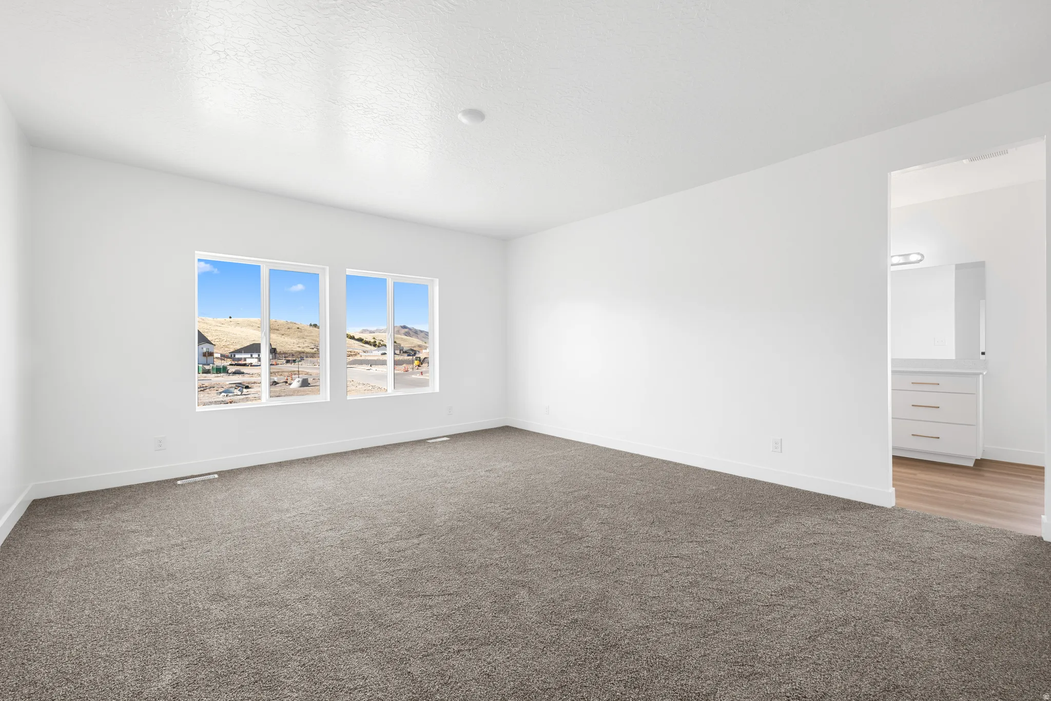 Empty room with light colored carpet and a textured ceiling