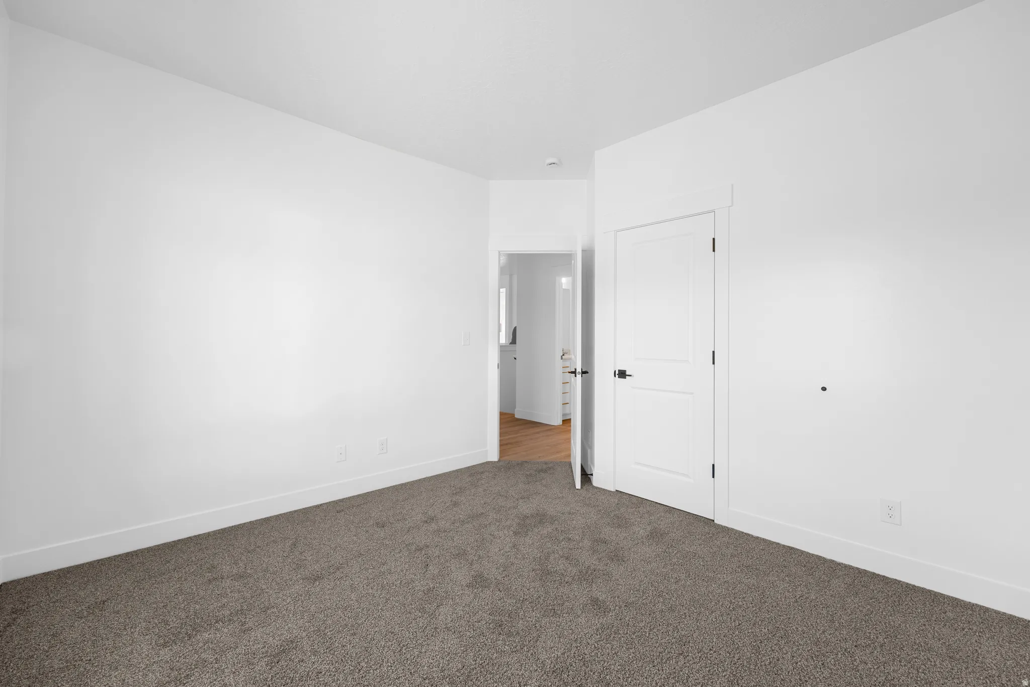 Unfurnished room with dark colored carpet and baseboards