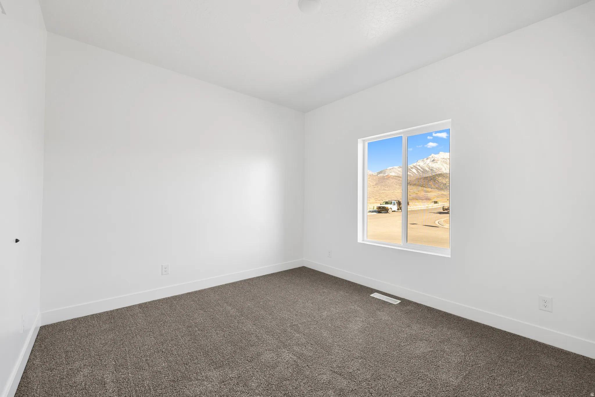 Empty room with dark colored carpet and a mountain view