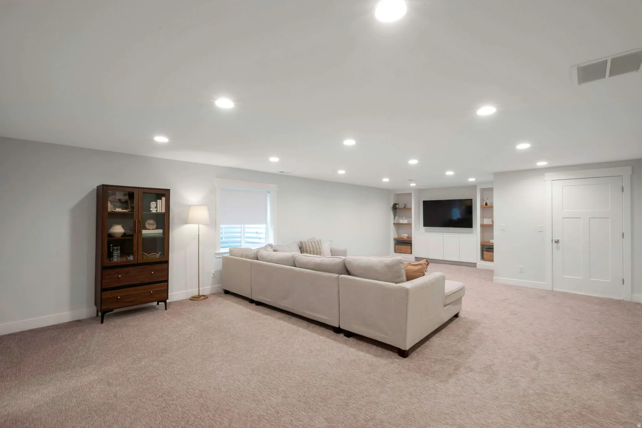 Living room featuring recessed lighting, light colored carpet, and built in shelves