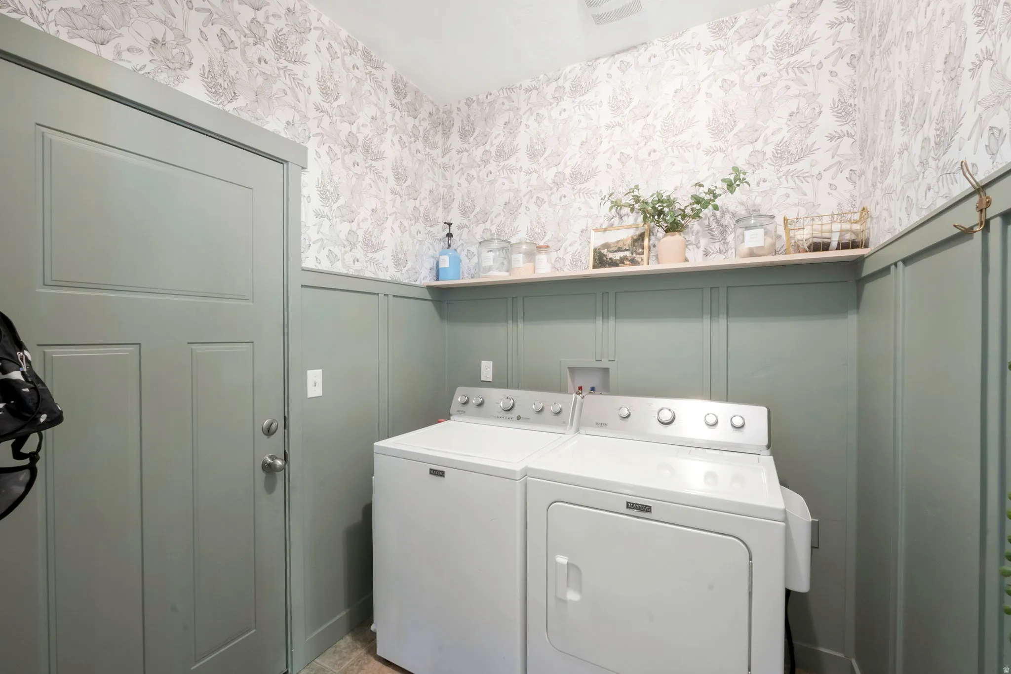 Laundry area with a decorative wall, wainscoting, independent washer and dryer, and wallpapered walls