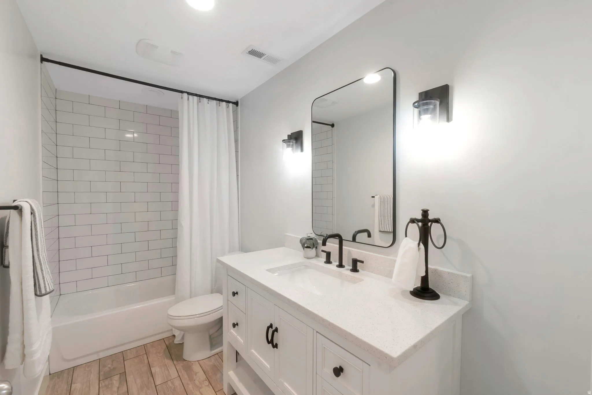Full bathroom featuring vanity, wood finish floors, and shower / bathtub combination with curtain