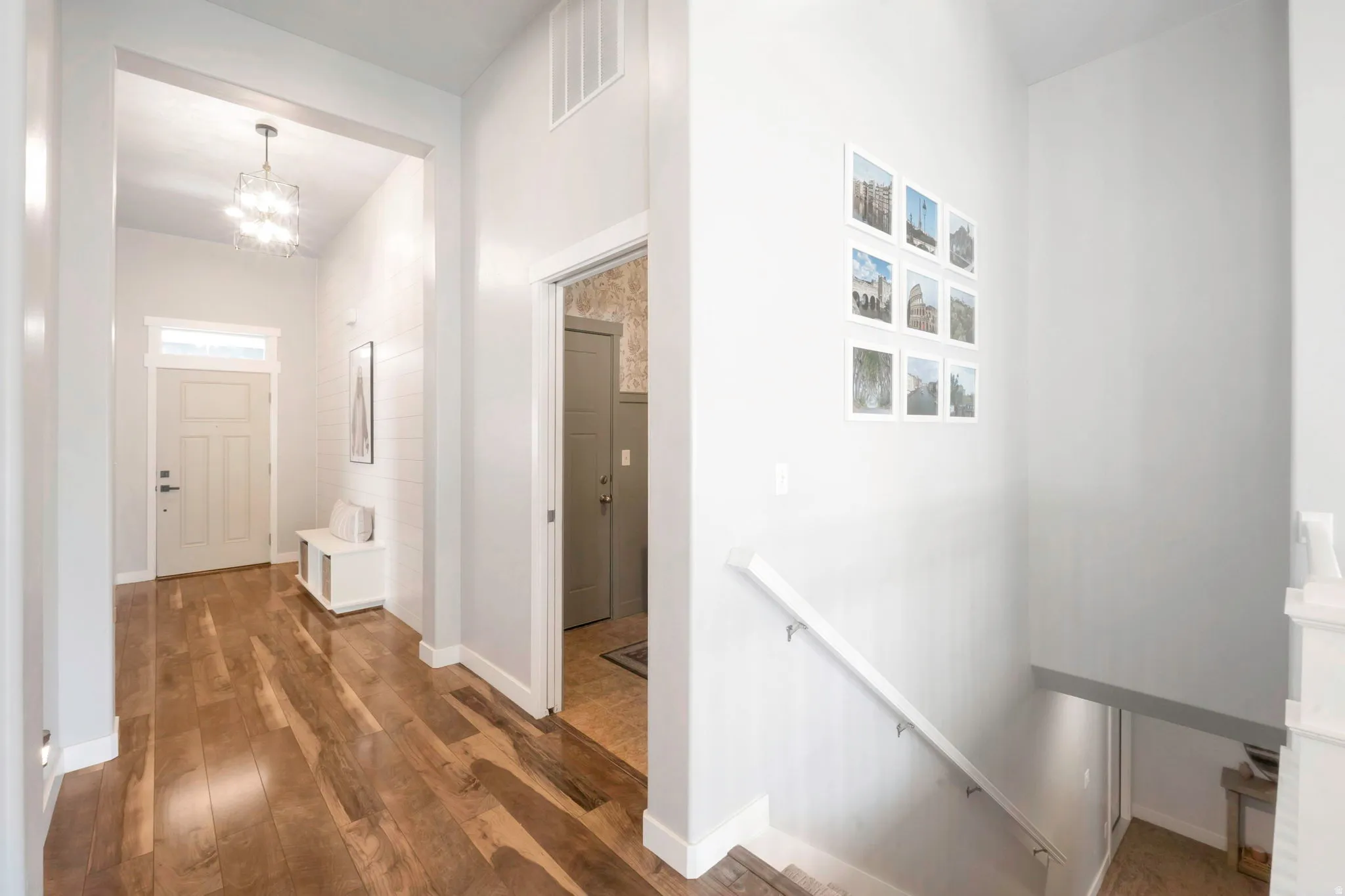 Hall with an upstairs landing, dark wood-style floors, and a chandelier