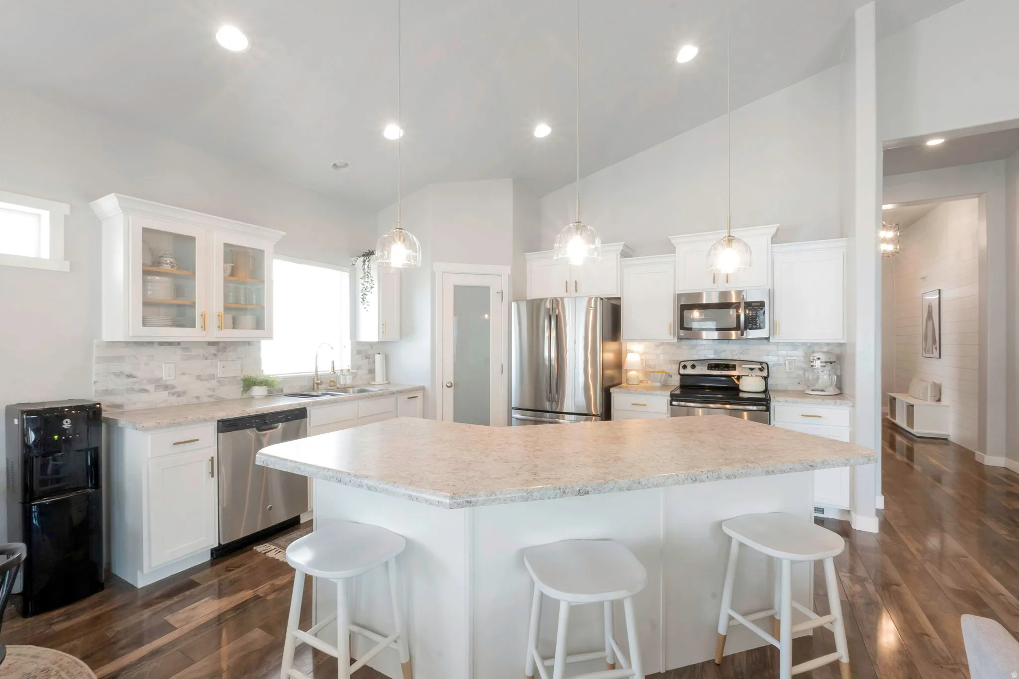 Kitchen with stainless steel appliances, white cabinets, backsplash, a kitchen breakfast bar, and lofted ceiling