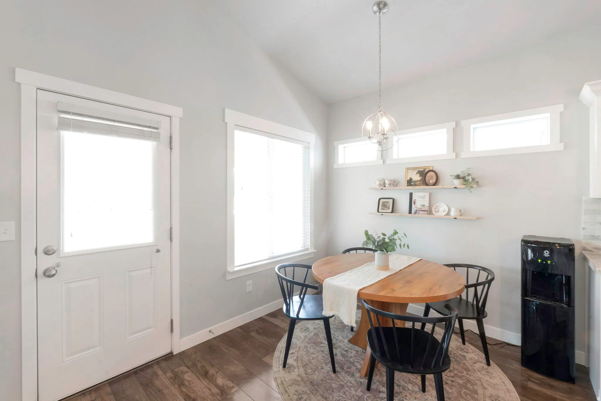 Dining room featuring dark wood-type flooring, lofted ceiling, and suspended lighting