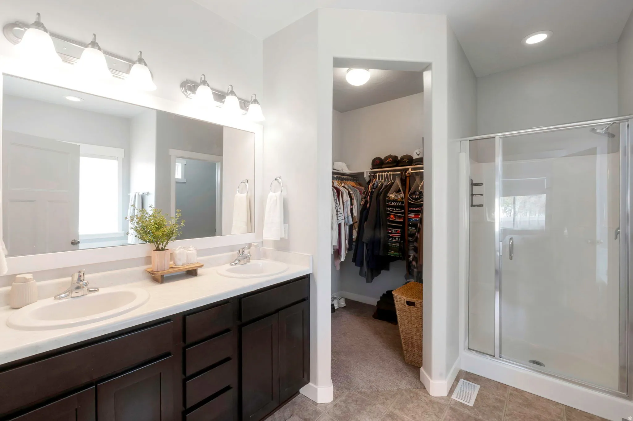 Full bathroom with double vanity, recessed lighting, a walk in closet, a stall shower, and light tile patterned flooring