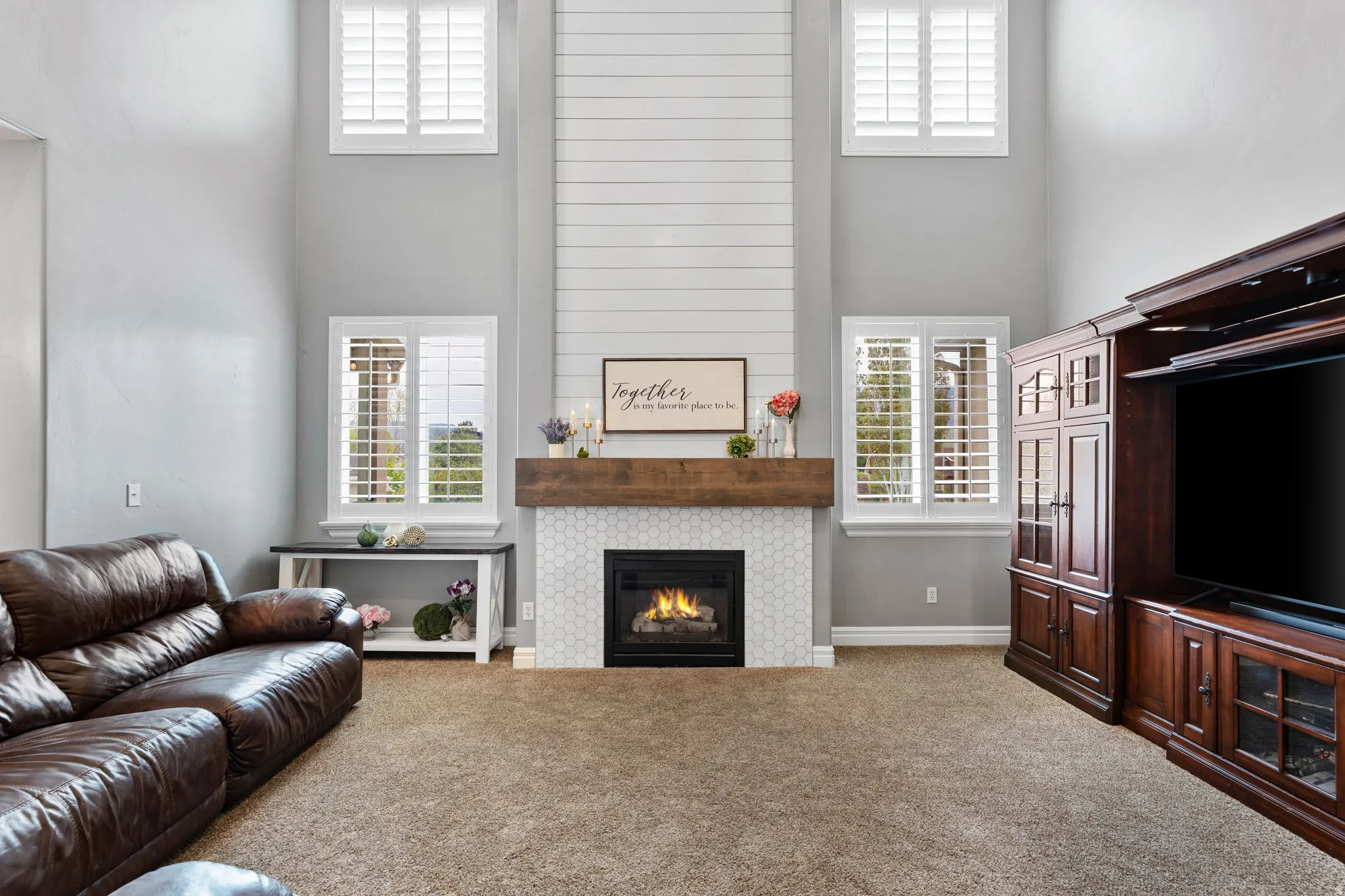 Carpeted living room with a high ceiling and a large fireplace