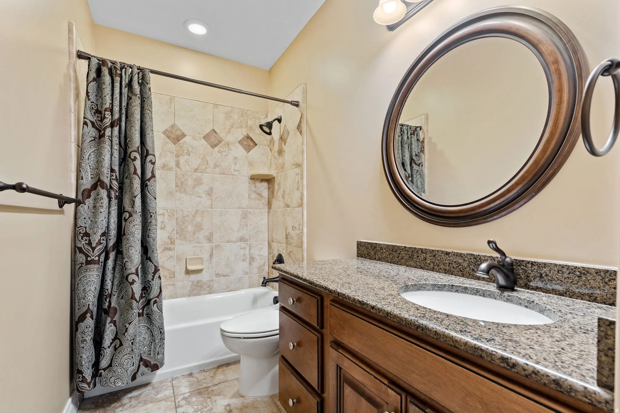 Bathroom featuring vanity, shower / bathtub combination with curtain, and light tile patterned flooring