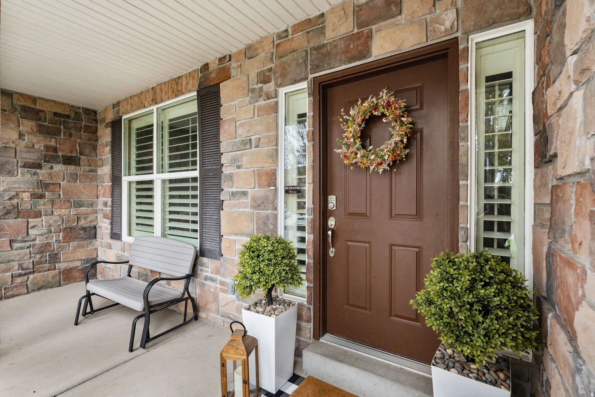 View of exterior entry with covered porch and stone siding