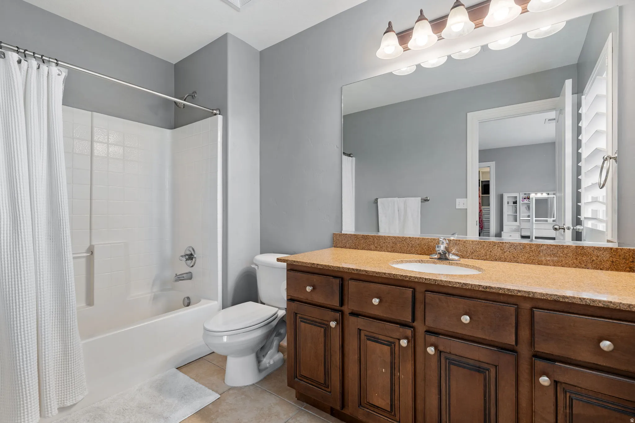 Bathroom featuring vanity, shower / bath combo, and light tile patterned floors